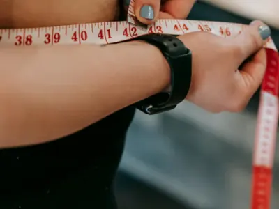 Woman measuring her waist with a tape measure